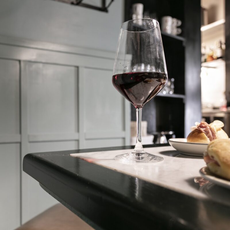 calice di vino rosso e panini farciti con salumi per aperitivo