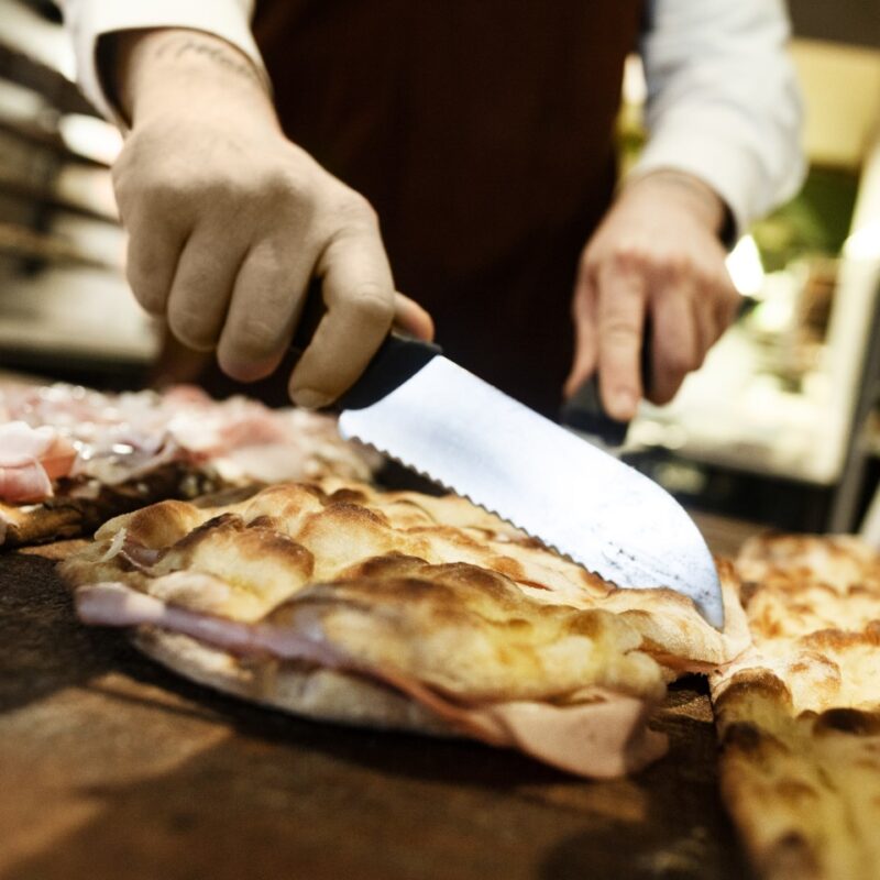 pizzaiolo taglia pizza alla pala bianca con mortadella